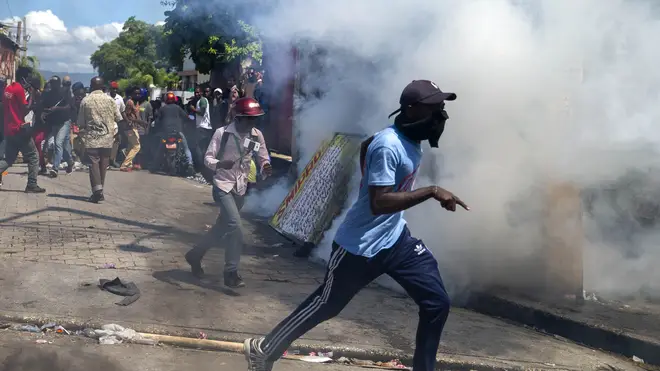Protesters run from tear gas launched by police to disperse protesters demanding the resignation of President Jovenel Moise in Port-au-Prince, Haiti (Dieu Nallo Chery/AP)