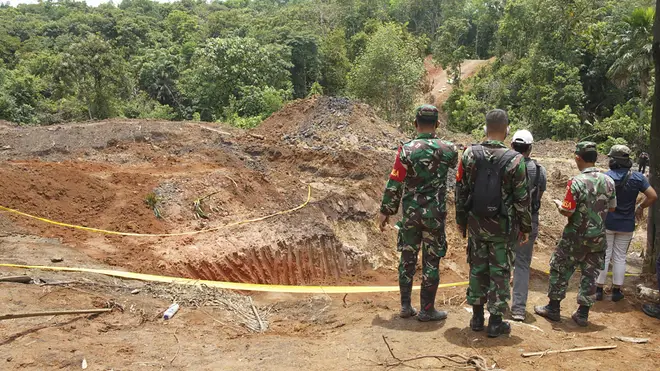 Military personnel inspect the site of a landslide at a coal mine in Muara Enim, South Sumatra