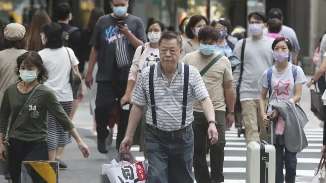 People wear face masks to protect against the spread of coronavirus as they walk through a shopping district in Taipei, Taiwan (Chiang Ying-ying/AP)