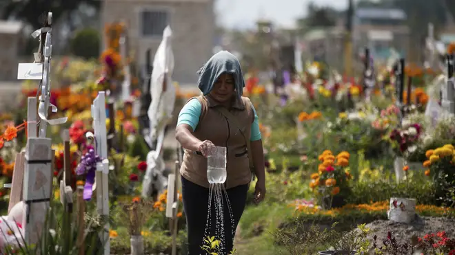 A woman waters her father’s grave at the Valle de Chalco municipal cemetery on the outskirts of Mexico City (Fernando Llano/AP)