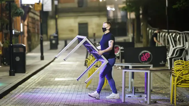 A bar worker packs tables and chairs away