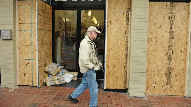 A pedestrian walks past a boarded up shop in Washington DC