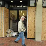 A pedestrian walks past a boarded up shop in Washington DC