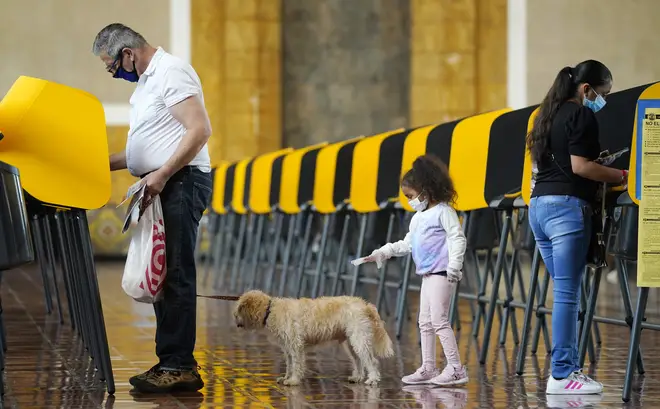 As Thomas Frieburger, left, and Lourdes Santos, right, vote on Election Day, Santos' daughter Sofia, 4, tries to get the attention of Frieburger's dog Lucky at a polling place at Union Station,