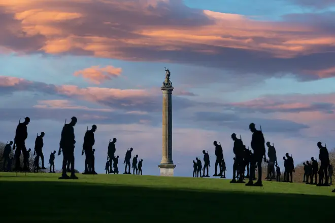 Silhouetted soliders at sunrise with Blenheim Palace's Column of Victory in the background