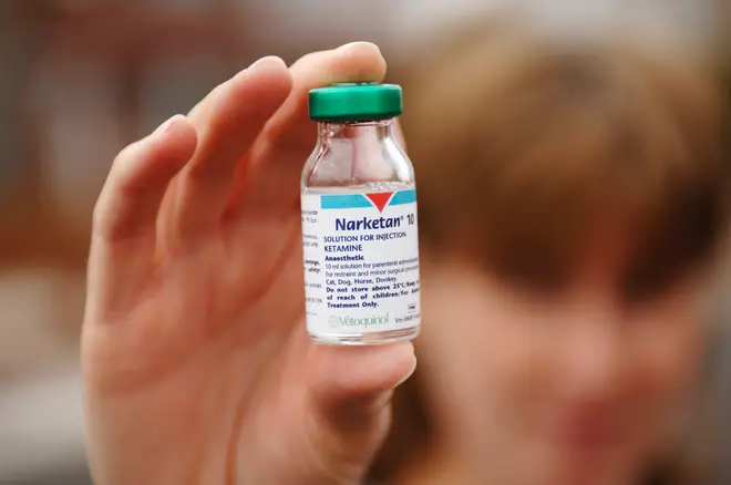 A person holding up a bottle of ketamine.
