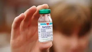 A person holding up a bottle of Ketamine.