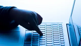 A child’s hand pressing a key on a laptop