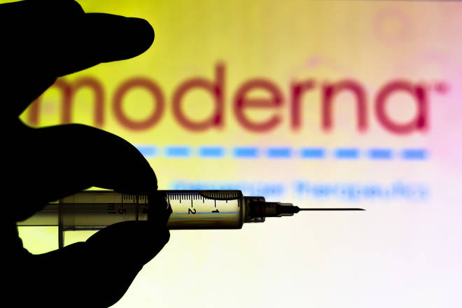 File photo: A medical syringe is seen with Moderna Therapeutics company logo displayed on a screen in the background