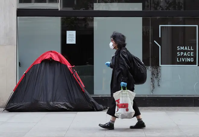 File photo: A woman walking past a homeless person's tent erected outside a furniture store in Tottenham Court Road, London