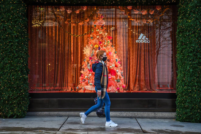A woman wearing a face mask passes a Christmas window display on Oxford Street, London