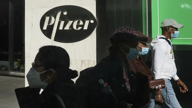 Masked pedestrians walk past Pfizer's world headquarters in New York