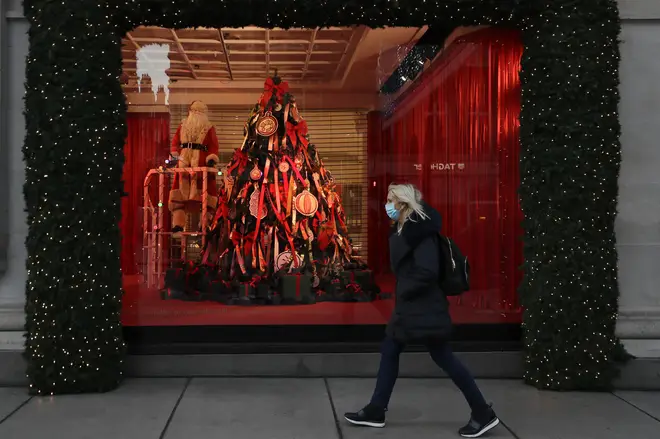 A woman walks past Christmas decorations in a shop window on Oxford Street