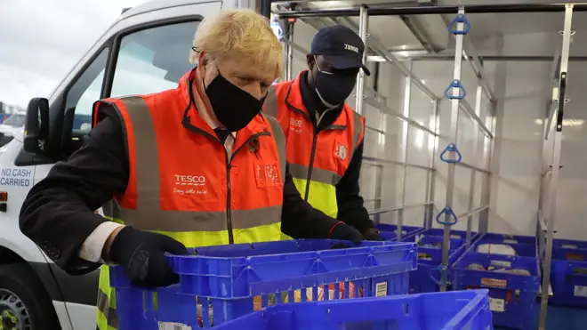Boris Johnson loads a delivery van with baskets of shopping during a visit to the Tesco Erith distribution Centre in south east London