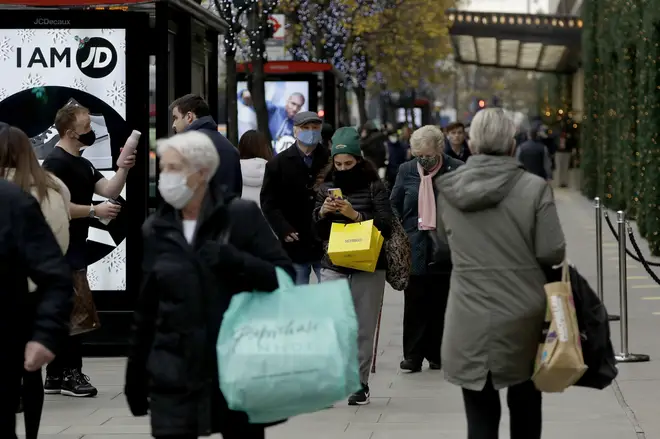 People carry shopping bags as non-essential shops are allowed to reopen