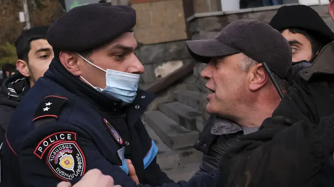 A police officer tries to detain demonstrators during a rally demanding the resignation of Armenia's PM