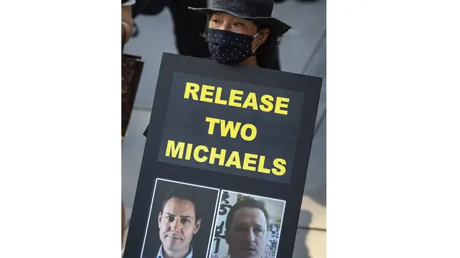 A woman holds a sign showing Michael Kovrig and Michael Spavor