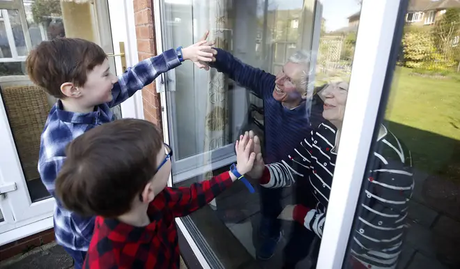 Ben and Isaac talk to their grandparents Sue and Alan through a window, as they self-isolate at their home