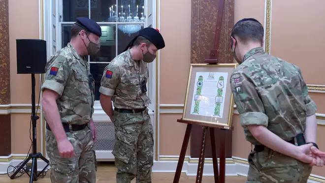 Soldiers look at the scroll that was presented to Brigadier Joe Fossey