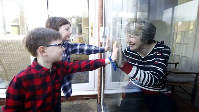 Ben and Isaac talk to their grandmother Sue through a window as she self-isolates at her home