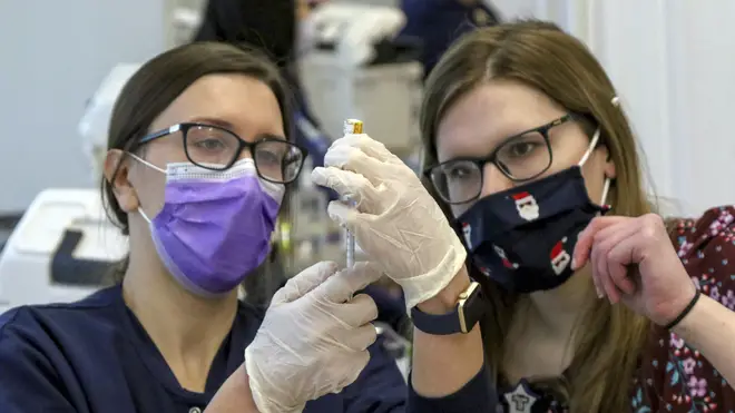 Registered nurse Natalie Chermel, left, and pharmacist Whitney Rader draw a dose of Covid-19 vaccine into a syringe
