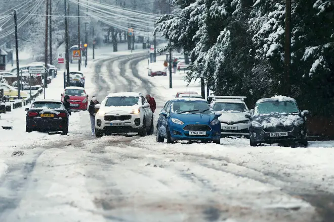 Members of the public help a car that is stuck in the snow as heavy snowfall falls down in Stourbridge, West Midlands