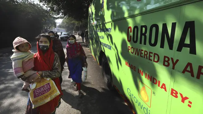 A family wearing face masks walks past a mobile clinic set up to test for Covid-19 in New Delhi, India