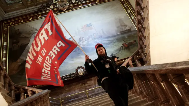 A protester holds a Trump flag inside the US Capitol Building near the Senate Chamber