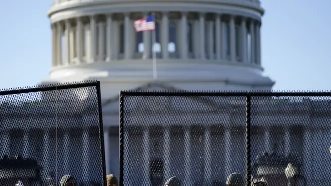 With the US Capitol in the background, authorities stand behind newly placed fencing (Evan Vucci/AP)