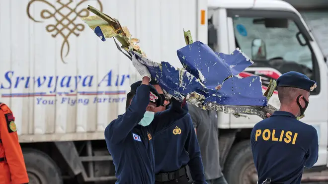Police officers carry a part of aircraft recovered from the Java Sea where a Sriwijaya Air passenger jet crashed
