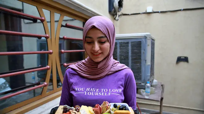 Fatima Ali shows her takeaway cheese-plate that she sells making a small but steady income, in Baghdad, Iraq
