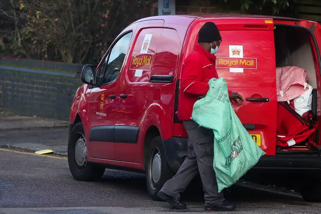 File photo: A postman wearing a face mask holds a postal sack in London