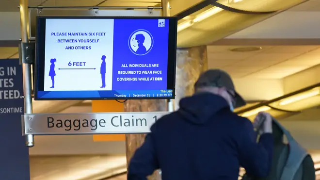 An electronic sign advises travellers to wear face masks and practice social distancing while passing through the main terminal of Denver International Airport