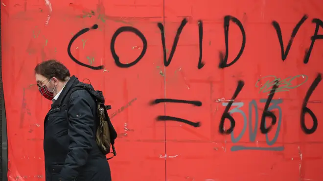 A man walks past coronavirus graffiti in Edinburgh where stricter lockdown measures for mainland Scotland are now in force