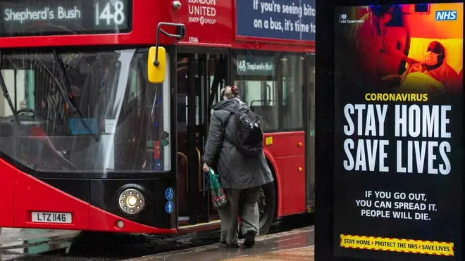 A bus stops by a government coronavirus 'stay home, save lives' advert in central London
