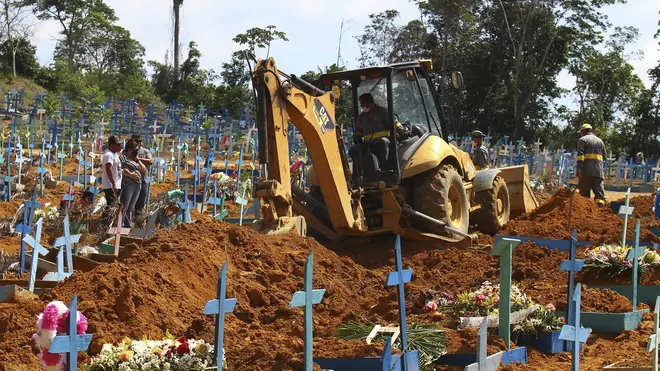 A bulldozer moves earth over a coffin in Manaus, Brazil (Edmar Barros/AP)