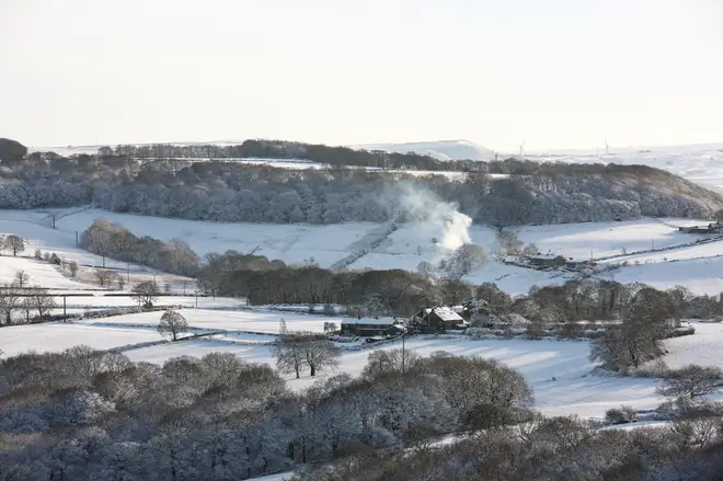 Smoke rises from a chimney in the snow-covered West Yorkshire landscape