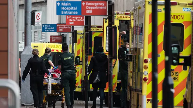 Paramedics transport a patient with visible oxygen tank from the ambulance to the emergency department at the the Royal London Hospital