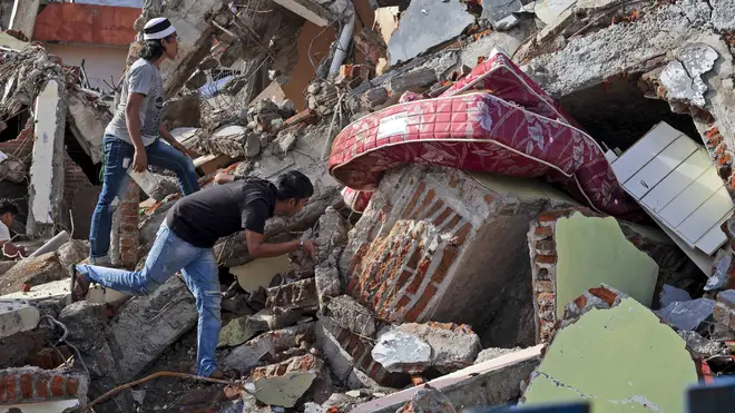 Residents inspect a building collapsed in Friday’s earthquake in Mamuju, West Sulawesi, Indonesia