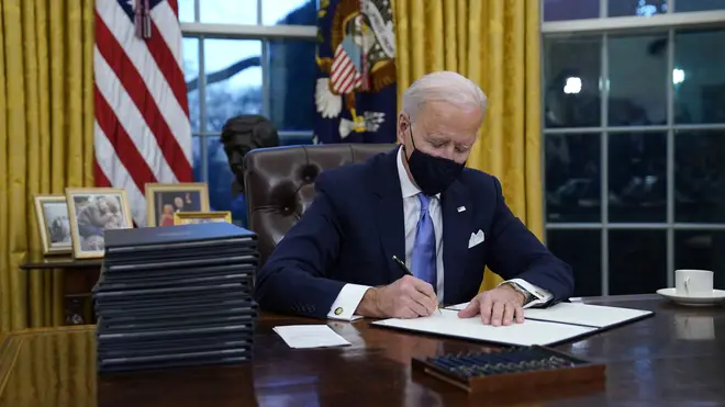 President Joe Biden signs his first executive order in the Oval Office (Evan Vucci/AP)