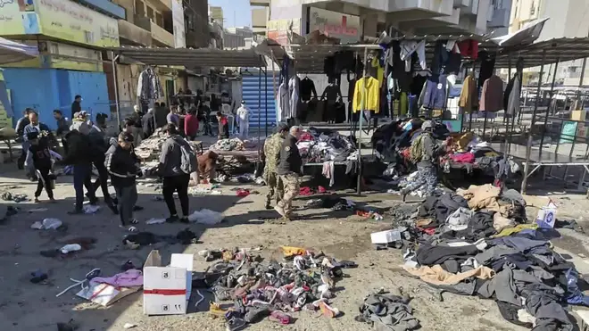 People and security forces gather at the site of a deadly bomb attack in a market selling used clothes in Iraq