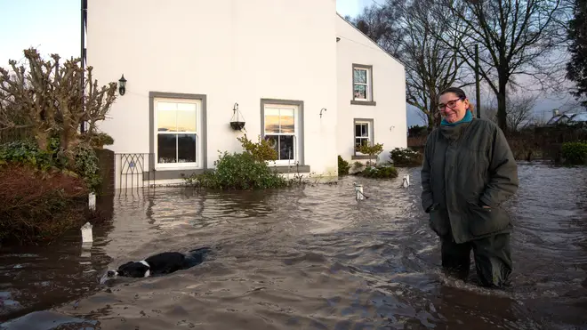 Ms Burns-Smith and her dog Tag outside their flooded home on the outskirts of Lymm in Cheshire