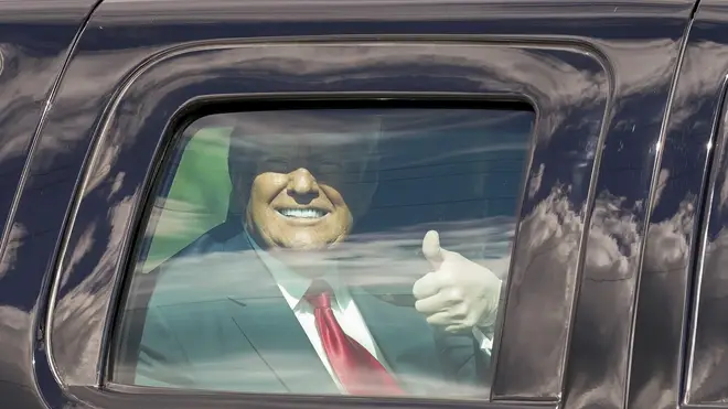President Donald Trump gestures to supporters from inside a vehicle
