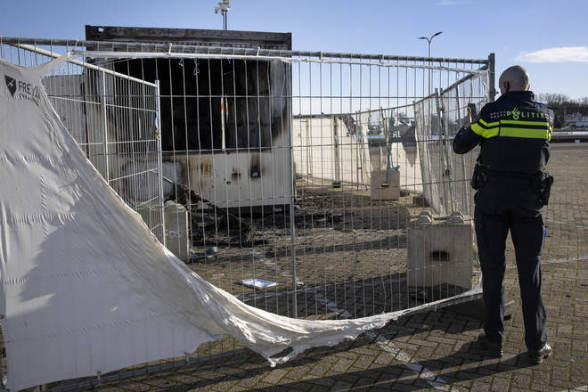 A police officer takes images of a torched coronavirus testing facility in the Dutch fishing village of Urk.