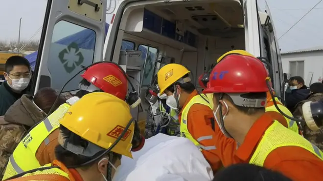 Rescuers carry a miner who was trapped in a gold mine