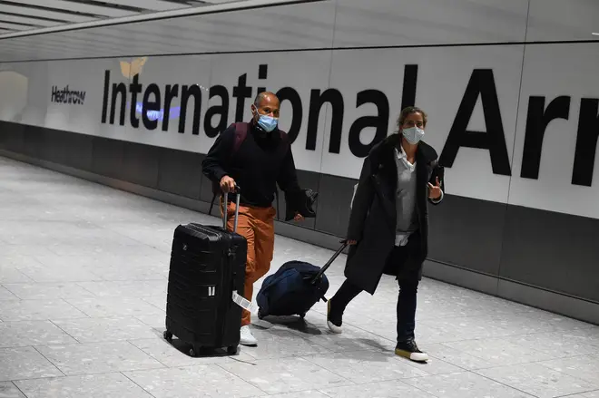 Passengers walk with luggage through the Arrival Hall of Terminal 5 at London's Heathrow Airport