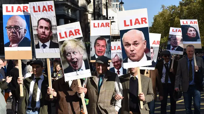 Protesters hold up placards with the word "liar" written next to photos of prominent Brexiteers