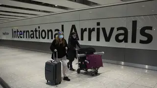 Passengers walk in the arrivals area at Heathrow Airport