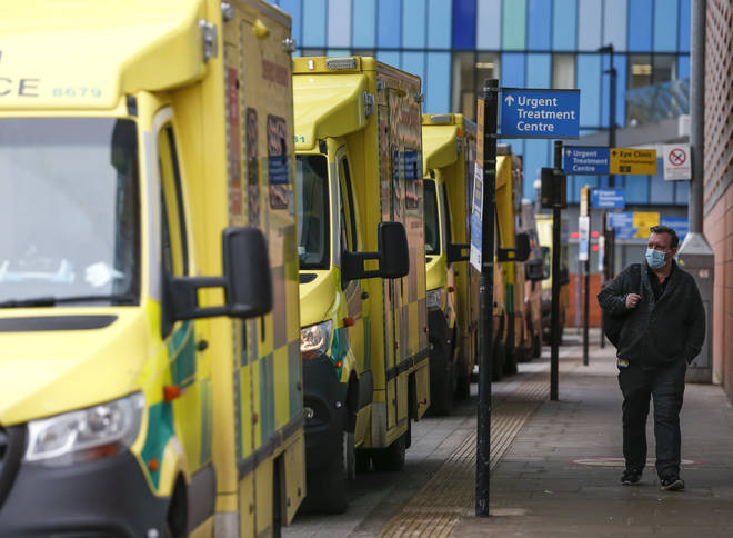 File photo: A man wearing a face mask walks past ambulances at The Royal London Hospital