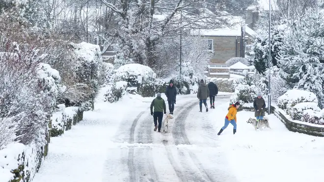 People walk along a snow-covered lane in West Yorkshire